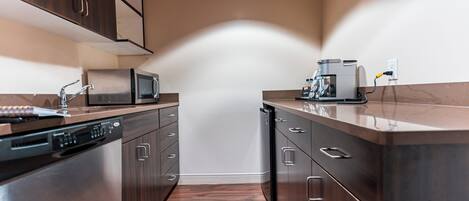 A modern kitchen with stainless steel appliances, wooden cabinets, and a built-in microwave.