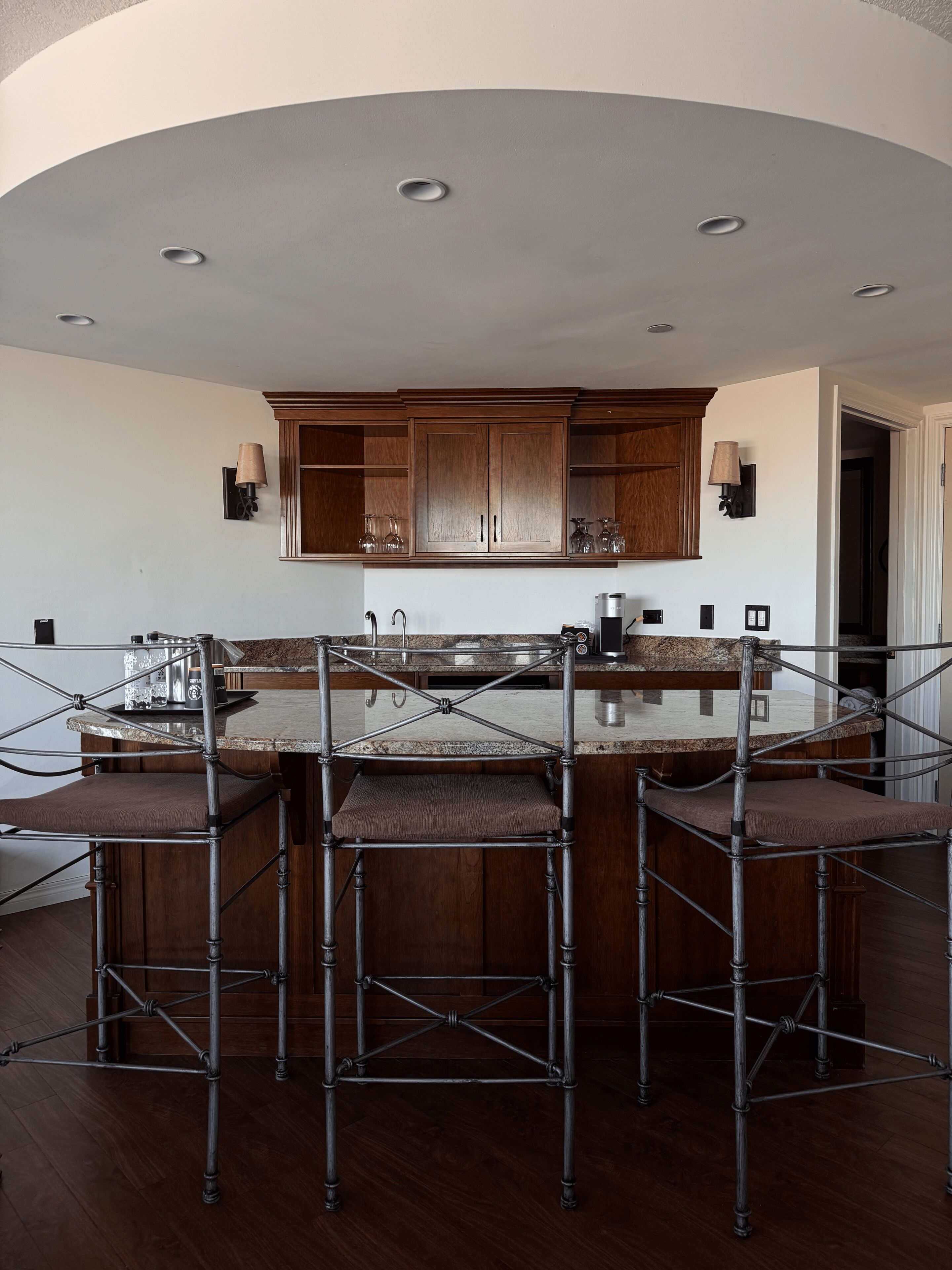 A kitchen with a central island, wooden cabinets, and bar stools.