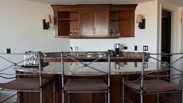 A kitchen with a central island, wooden cabinets, and bar stools.