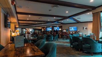 A hotel lobby with multiple seating areas, a bar, and several televisions displaying content.