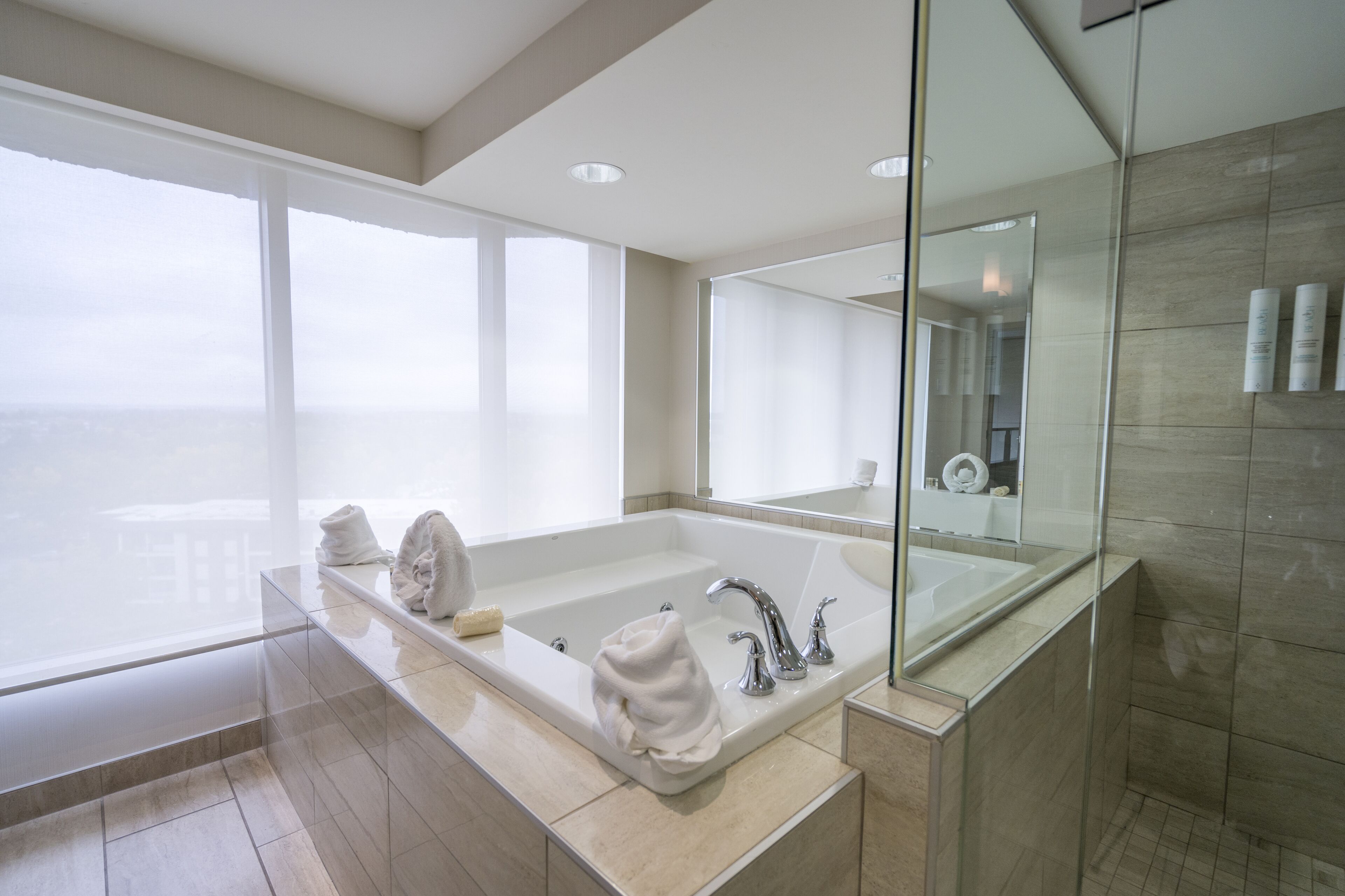 Un bagno moderno con una grande vasca, uno spazio doccia in vetro e un ampio specchio.