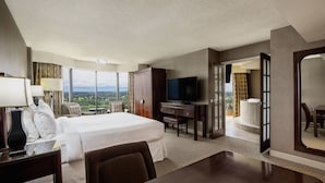 Una habitación de hotel con una cama grande, un escritorio, televisión y vistas a la ciudad.