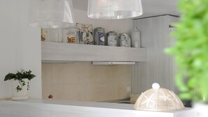 Una cucina moderna con un piano di lavoro bianco, lampade a sospensione e una macchina per il caffè.