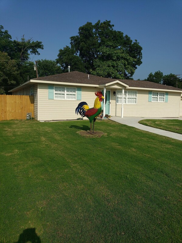 A residential house with a front yard and a large rooster statue.