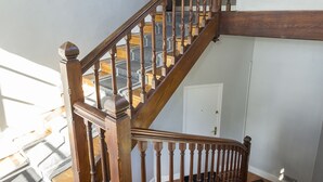 A wooden staircase with a handrail, carpeted steps, and a door at the bottom.