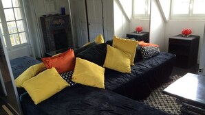 A modern living room with a dark blue sofa and yellow pillows, a patterned rug, and a fireplace.