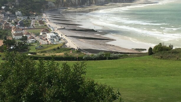 A coastal town with a beach, houses, and cliffs.