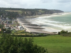 A coastal town with a beach, cliffs, and residential buildings. - The beach in Normandy (Hautot sur mer)