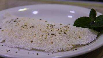 Un plato blanco con un alimento blanco, posiblemente queso, decorado con hierbas.