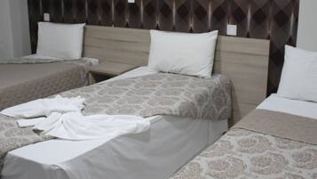 A hotel room with three beds, each with a different patterned bedspread.