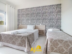 A hotel room with two beds, a zebra-patterned wall, and a window with curtains.