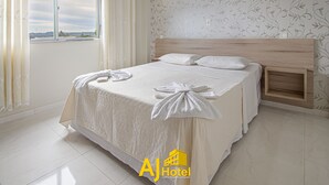 Una habitación de hotel con una cama grande, cabecero de madera y vistas por una ventana.