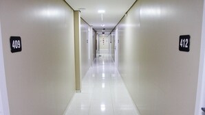 Un pasillo largo y estrecho con pisos de baldosas blancas y paredes color crema. Se ven puertas numeradas a ambos lados, con indicaciones de los números de habitación 409 y 412.