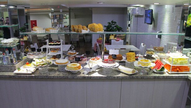Un mostrador de buffet con diversos alimentos y una pantalla de televisión en la pared.