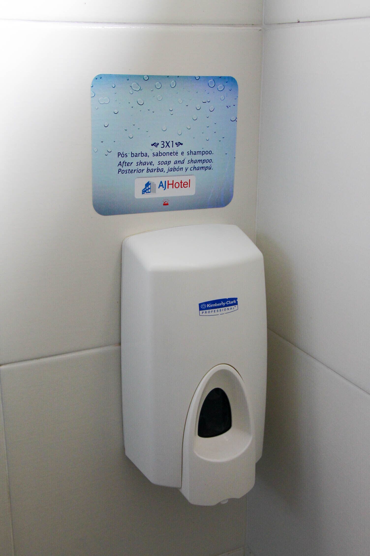 A restroom with a soap dispenser and a sign above it.