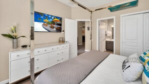 Un dormitorio con una cama, un aparador, un televisor y un ventilador de techo.
