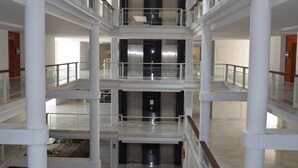 A multi-level interior with white columns, glass railings, and a central elevator. - Parque Botanico Holiday Rentals (Estepona)