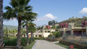 A residential area with modern houses, a paved driveway, and palm trees. - Parque Botanico Holiday Rentals (Estepona)
