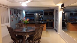 Una cocina moderna con armarios oscuros, una isla central y un comedor con una mesa redonda y sillas.
