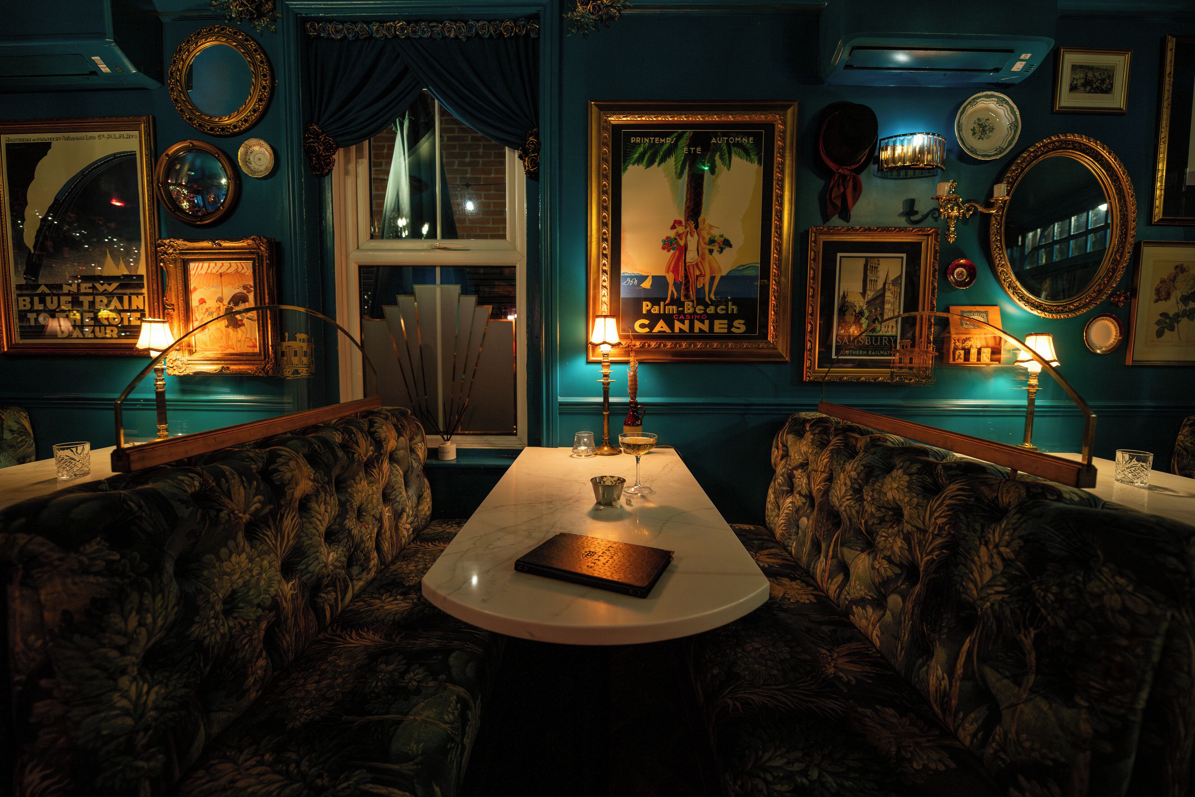 A room with a round table, floral-patterned sofas, and various framed pictures and mirrors on the walls.