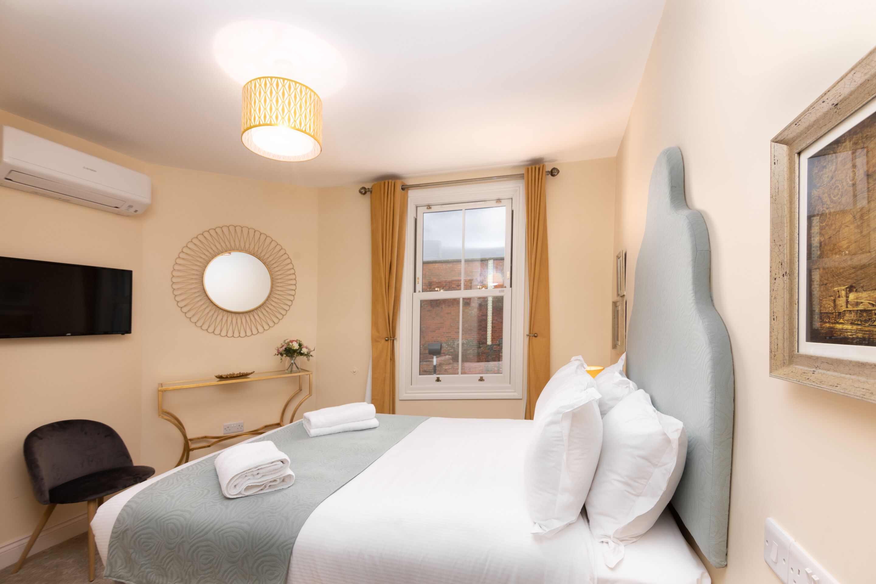 A hotel room with a bed, a TV, a desk, and a window.