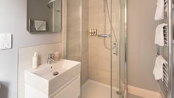 A modern bathroom with a glass-enclosed shower, a white sink, and a mirror above it.