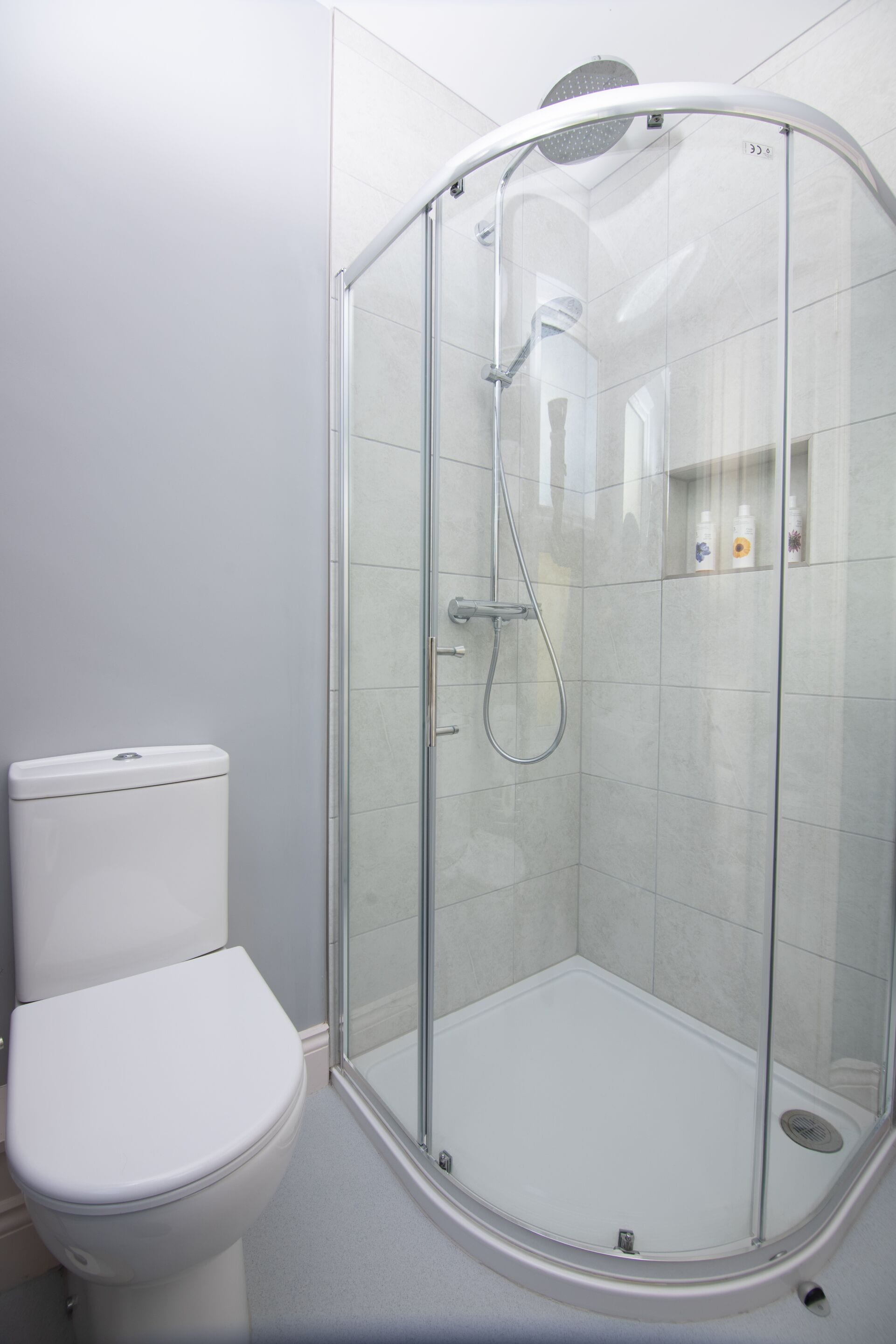 Un baño moderno con ducha de vidrio, inodoro blanco y piso de baldosas.