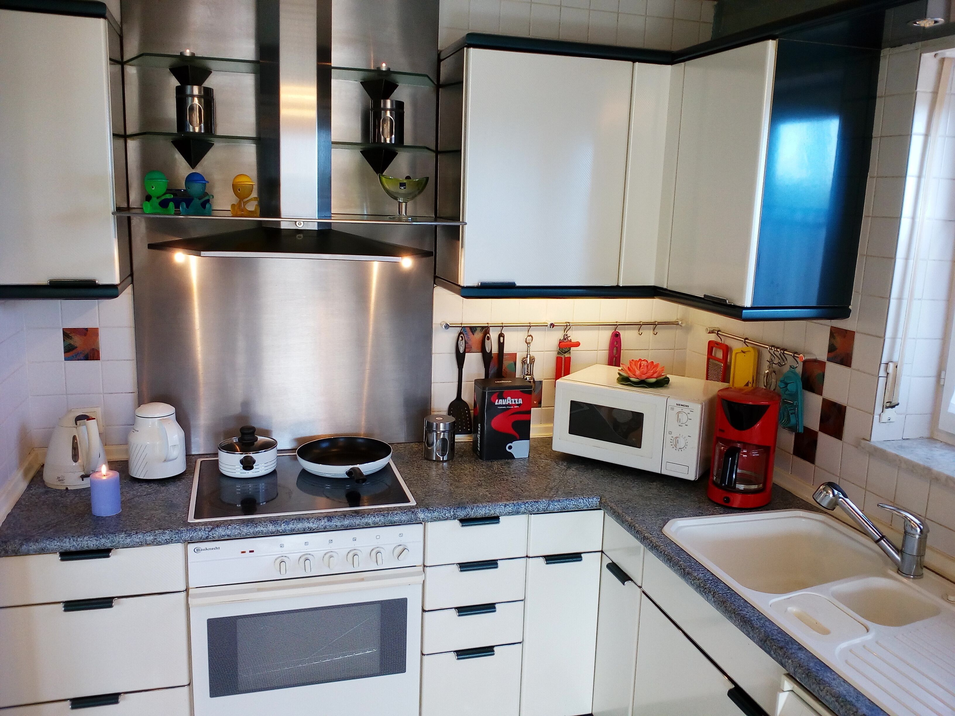 Une cuisine avec des meubles blancs, une cuisinière, un four à micro-ondes et un évier.