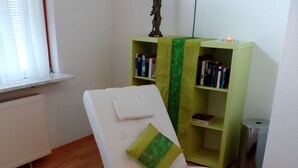 Un saló modern amb una butaca blanca, una taula de centre de vidre i una estanteria verda.