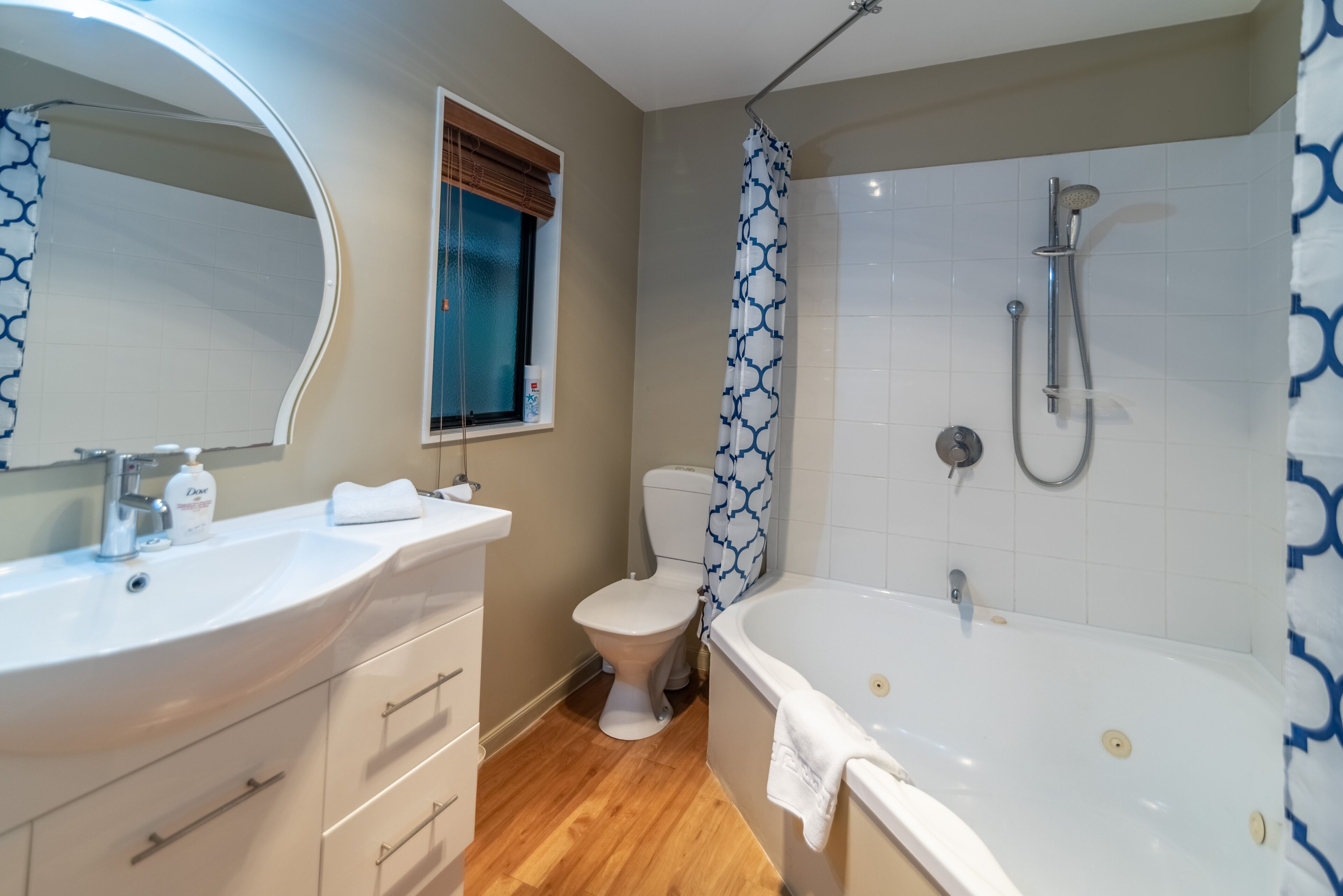 Une salle de bain avec un lavabo blanc, des toilettes, une douche avec un rideau à motifs bleus et une baignoire.
