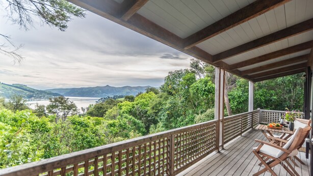 Una terraza de madera con vistas a un lago y montañas.