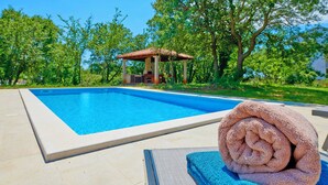 A swimming pool with a tiled deck, a gazebo, and a rolled towel on a lounge chair. - Villa Theresa in Ližnjan (Haus für 12 Personen) (Liznjan)