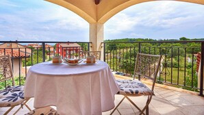 A balcony with a table set for two, overlooking a residential area with houses and greenery. - Villa Theresa in Ližnjan (Haus für 12 Personen) (Liznjan)