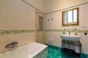 A bathroom with a bathtub, a sink, and a mirror.