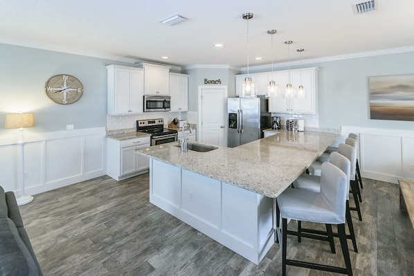 A modern kitchen with white cabinetry, a large island, stainless steel appliances, and pendant lighting. - Near Mayo Clinic 2 blocks from ocean 4 BR pet friendly perfect family home. (Jacksonville Beach)