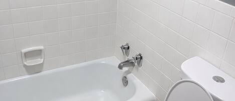 Une salle de bain avec une baignoire blanche, des toilettes et des murs carrelés.