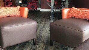 Un salon moderne avec des canapés en cuir, un téléviseur à écran plat, un coin repas avec des chaises rouges et un plancher en bois.