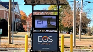 Une borne de recharge dotée d’un toit à panneaux solaires, portant l’inscription « EOS CHARGE », et d’un écran affichant « EOS LINX ».