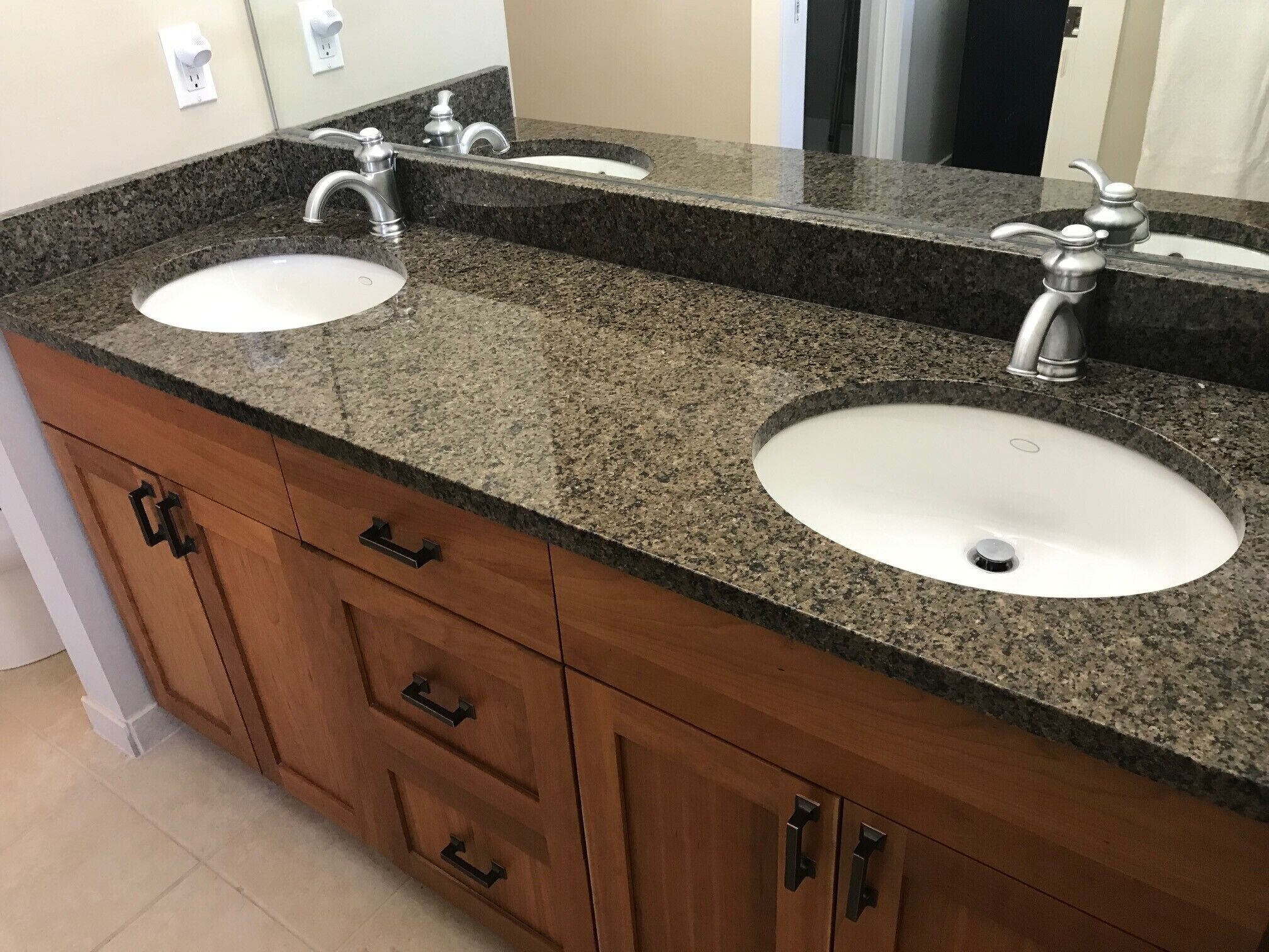 Un baño con dos lavamanos, un espejo y armarios de madera.