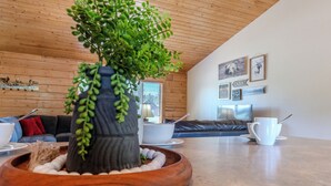 Una sala de estar acogedora, con techo de madera, una planta en maceta, un sofá y una mesa de centro.