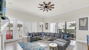 A modern living room with a sectional sofa, a coffee table, and a ceiling fan. - Ultimate Family Getaway | Game Room/Movie Theater, Private Pool, Custom Themed Rooms (Kissimmee)