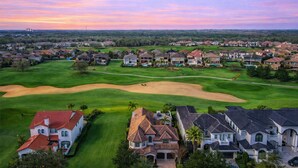 A residential area with houses, a golf course, and a sunset sky. - Ultimate Family Getaway | Game Room/Movie Theater, Private Pool, Custom Themed Rooms (Kissimmee)