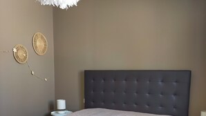 A bedroom with a large bed, a tufted headboard, a wall-mounted decorative item, and a small bedside table. - Grillon in the Enclave des Papes, 4 km from Château de Grignan.  (Grillon)