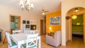 A dining area with a white table and chairs, a chandelier, and a ceiling fan. - Club Villamar - Nice house, complete and very sunny, located in a quiet urbanization,with a  priv... (Vidreres)