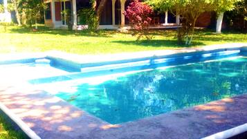Guests can enjoy a refreshing swim in the pool surrounded by lush greenery and a variety of trees.