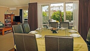 A dining area with a table set for four, a television, and a bookshelf in the background.