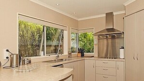 A modern kitchen with a large window, a stainless steel range hood, and a built-in sink.