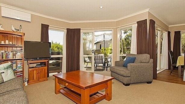A living room with a wooden coffee table, a grey sofa, a television, and a bookshelf.
