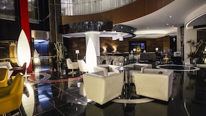 A modern lobby with a curved ceiling, a reception desk, and seating areas. - JF Grand Puebla (Puebla)