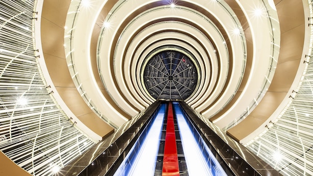 A modern architectural structure with a central escalator surrounded by concentric circular patterns. - JF Grand Puebla (Puebla)